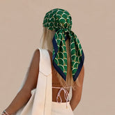 Modelo de espaldas con la pañoleta Esmeralda Doré verde de abanicos dorados, anudada en la cabeza con las puntas sobre el cabello.