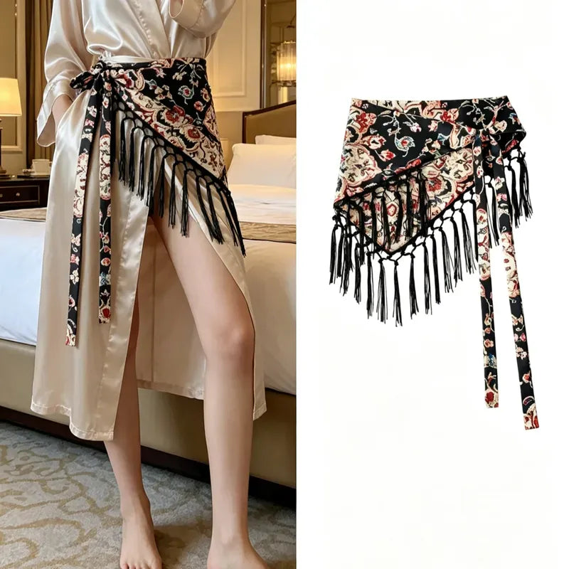 Cinturón pañoleta Bohemia Chic flora fondo negro con flecos, mostrado solo y anudado sobre un vestido claro.