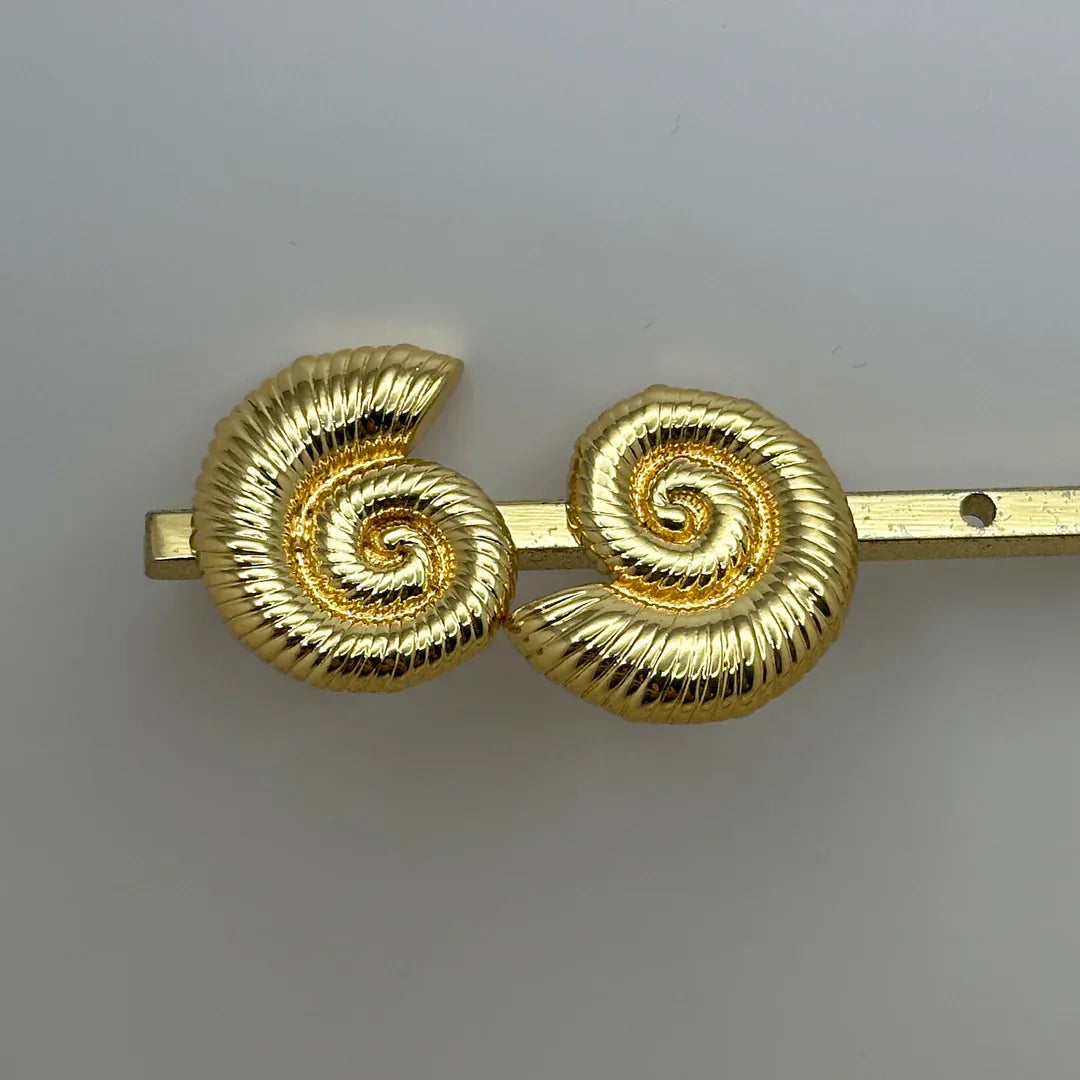 detalle de aretes dorados con diseño espiral marina sofisticado