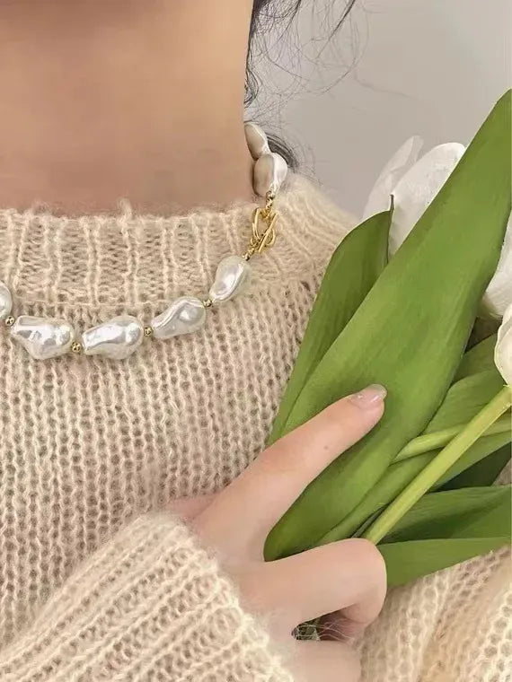 Modelo usando el collar Bahía Blanca de perlas esculturales doradas con un look elegante y moderno.
