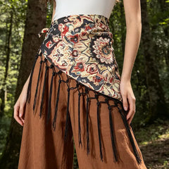 Modelo con cinturón pañoleta Bohemia Chic flora fondo negro y flecos negros sobre pantalón amplio terracota.