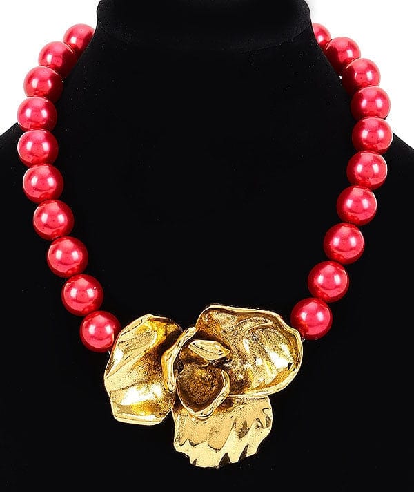 mujer usando collar rojo elegante con flor dorada statement