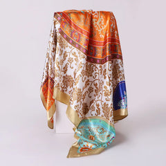 Detalle del estampado barroco de la pañoleta Soleá satinada para mujer en tonos naranja, dorado, marfil y turquesa.