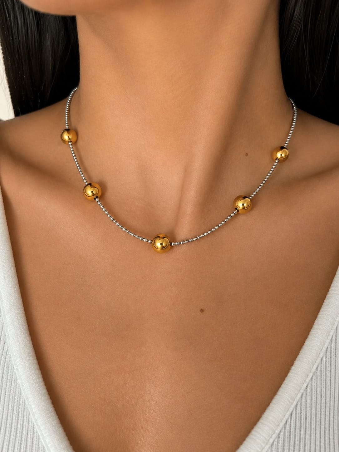 Collar bicolor Double Trouble con esferas doradas y cadena plateada lucido en el cuello