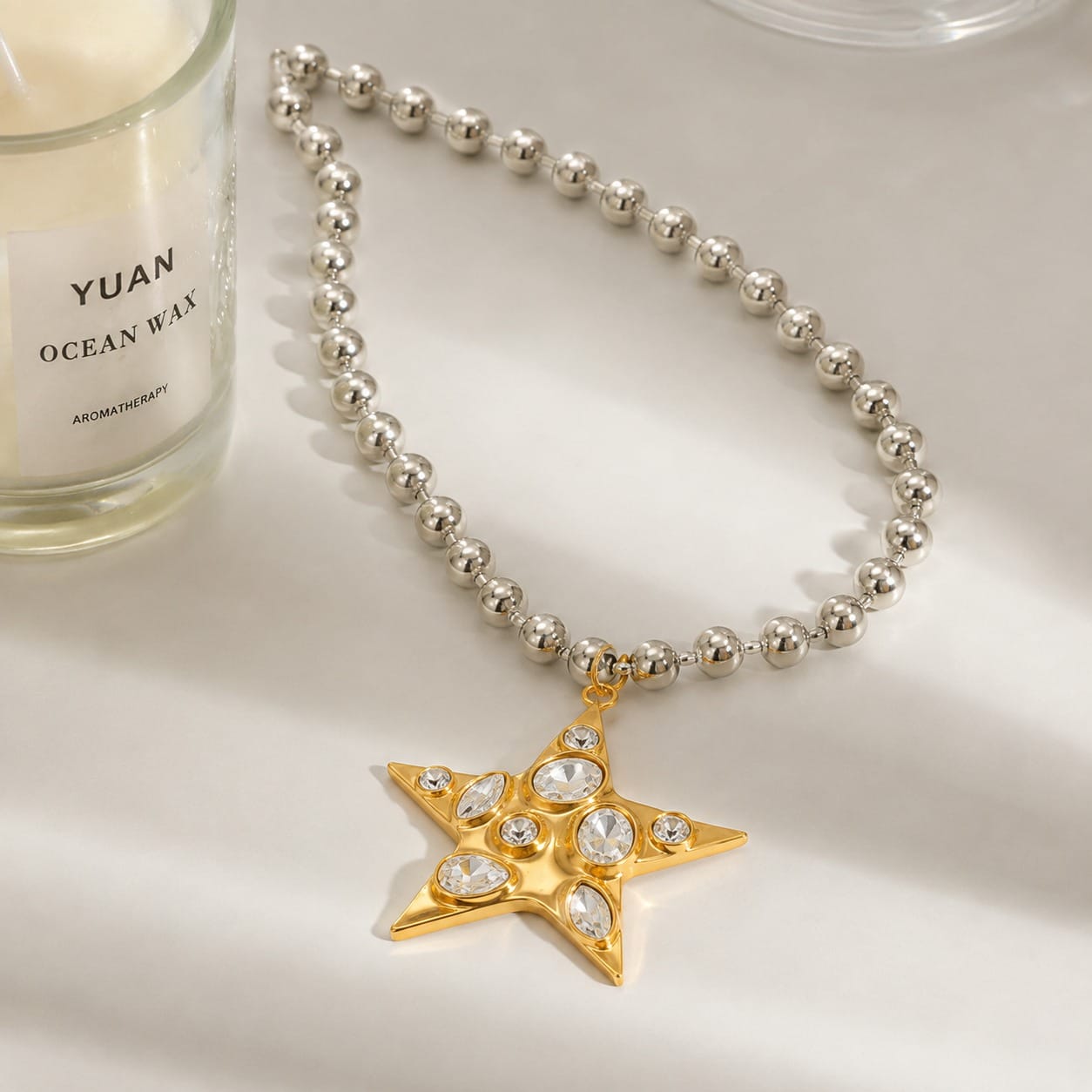  Collar de estrella dorada Estrella Nova con cadena plateada de cuentas sobre superficie clara
