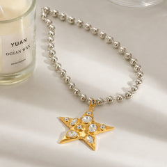  Collar de estrella dorada Estrella Nova con cadena plateada de cuentas sobre superficie clara