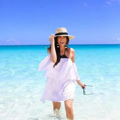 mujer caminando en la playa con sombrero fedora beige de ala media y cintillo negro
