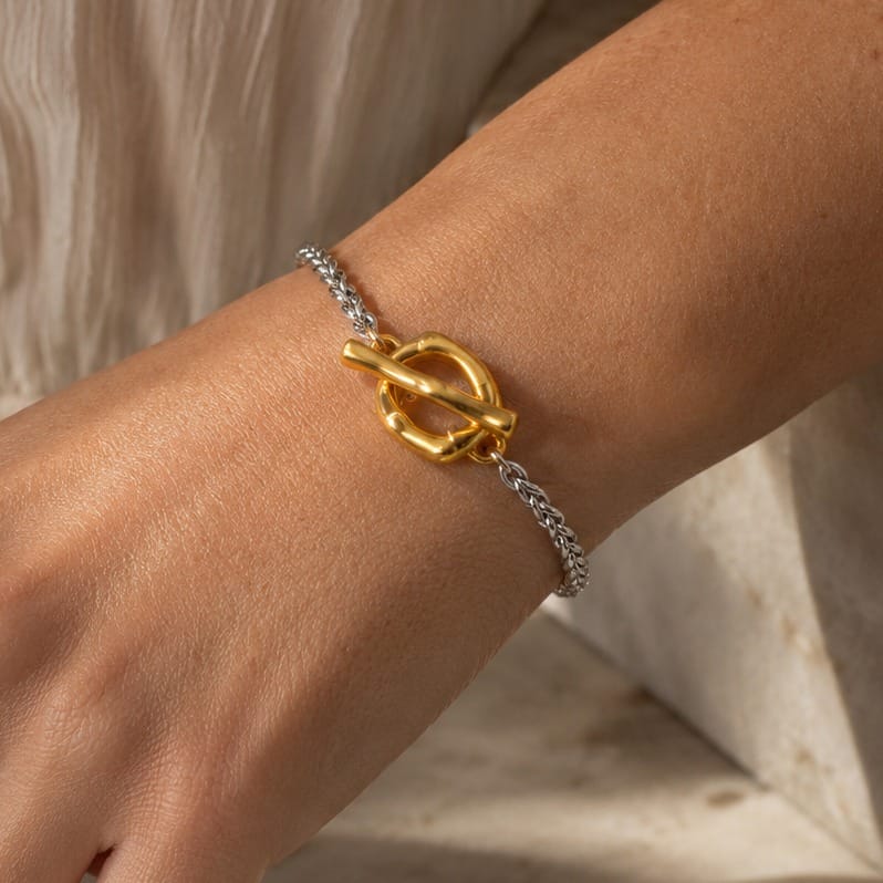 Pulsera Interlace de acero inoxidable bicolor con diseño minimalista y cierre tipo T-Bar en detalle puesta en la muñeca de una modelo