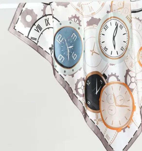 Pañoleta satinada de 70 × 70 cm con ilustración de relojes clásicos en tonos marfil, azul, negro y dorado.