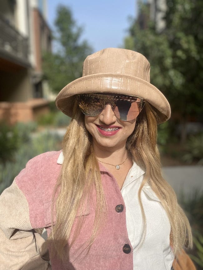 Modelo luciendo el Croc Luxe Bucket Hat color beige con acabado efecto cocodrilo en un look casual y elegante.